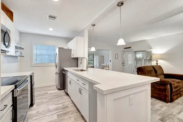 a large white kitchen with a stove a sink a refrigerator and a fireplace