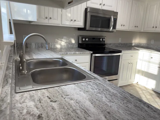 a kitchen with granite countertop a sink and a stove top oven
