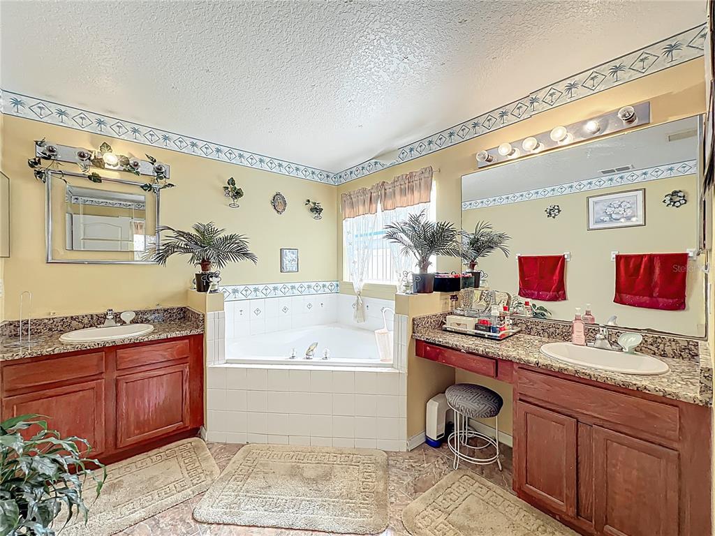 7939 Riffle Lane Orlando, FL 32818 - Photo 27 of 52 a spacious bathroom with a granite countertop sink and a mirror