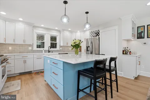 a kitchen with a sink stove and white cabinets with wooden floor