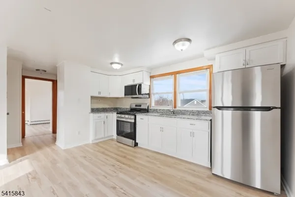 a kitchen with stainless steel appliances granite countertop a refrigerator a sink dishwasher a stove and white countertops with wooden floor