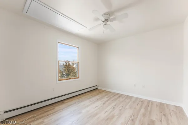 an empty room with wooden floor closet and windows