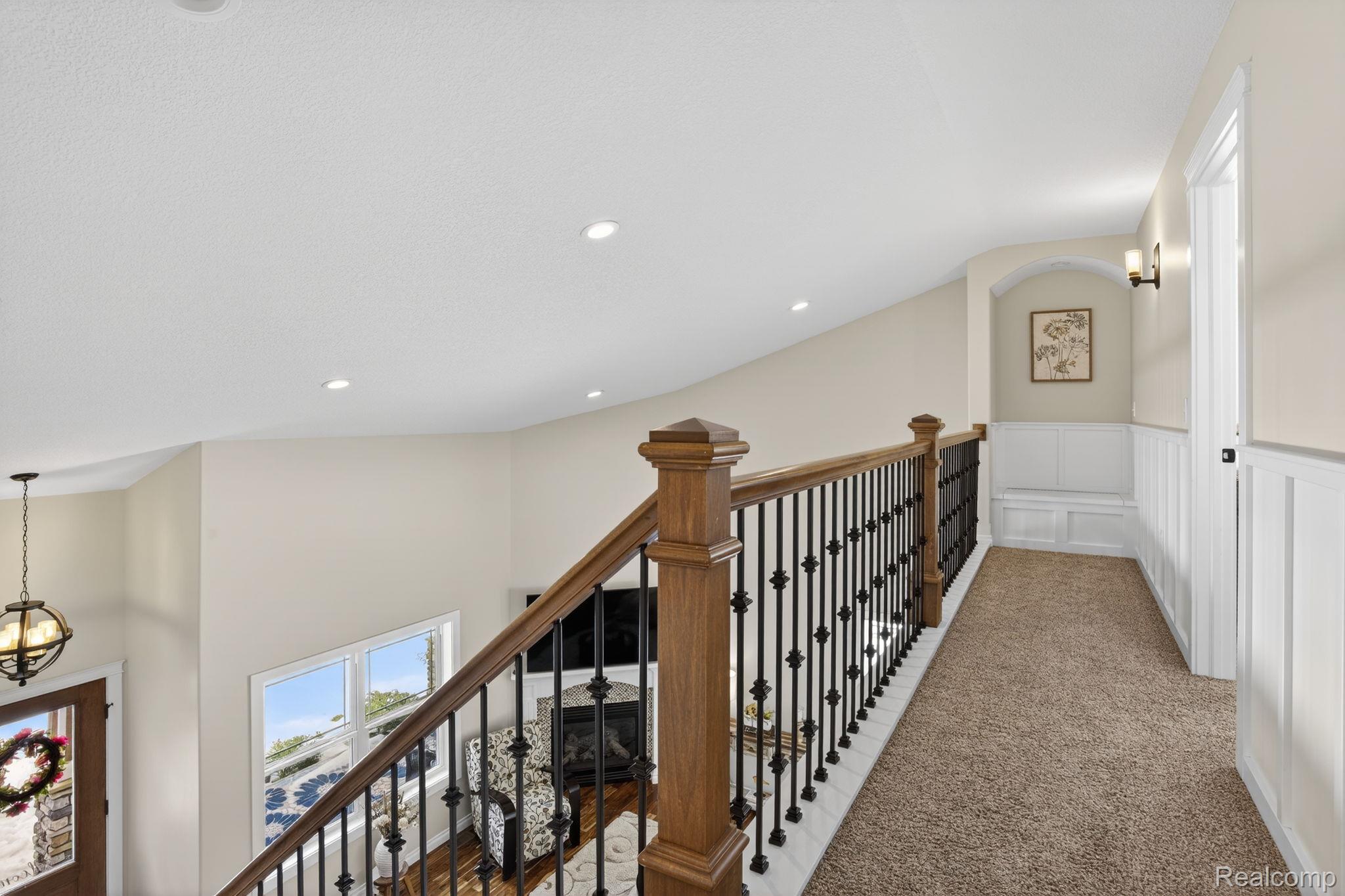 101 Highview Road Traverse City, MI 49696 - Photo 45 of 88 Corridor with carpet flooring, an upstairs landing, a decorative wall, wainscoting, and hanging lights