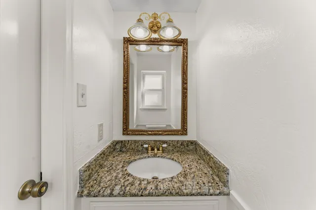 a bathroom with a granite countertop sink and a mirror