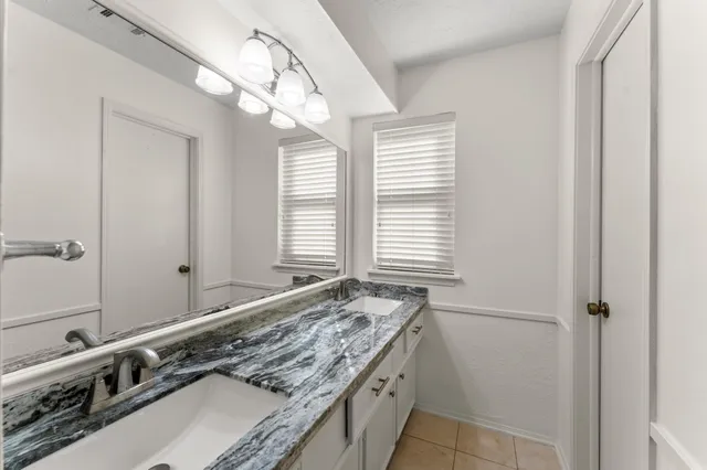 a bathroom with a granite countertop double vanity and a mirror