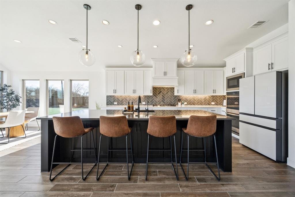 1551 Ripasso Way McLendon-Chisholm, TX 75032 - Photo 9 of 39 a kitchen with granite countertop a dining table chairs and white cabinets