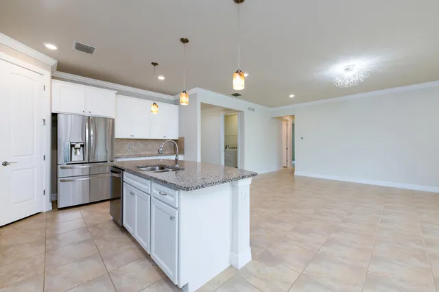 a kitchen with granite countertop a refrigerator sink and cabinets