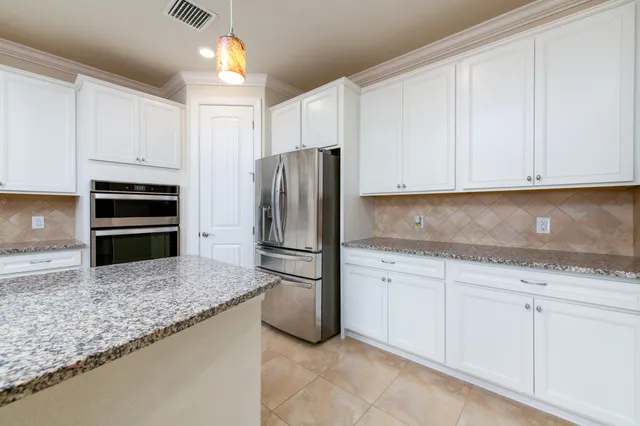 a kitchen with granite countertop white cabinets and stainless steel appliances