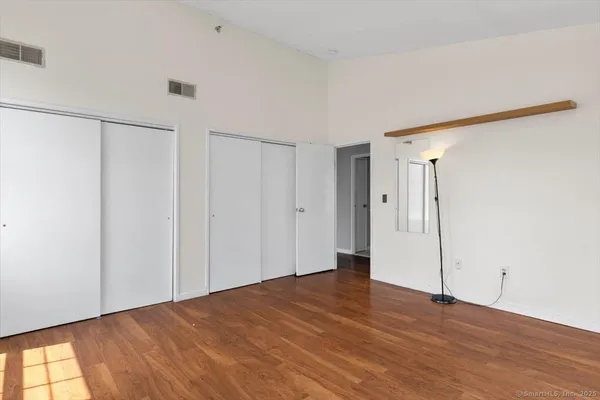 a view of empty room with wooden floor and white walls