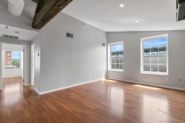 a view of empty room with wooden floor and fan
