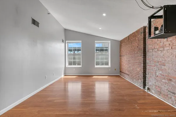 a view of an empty room with wooden floor and a window