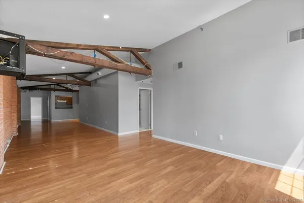 an empty room with wooden floor and windows