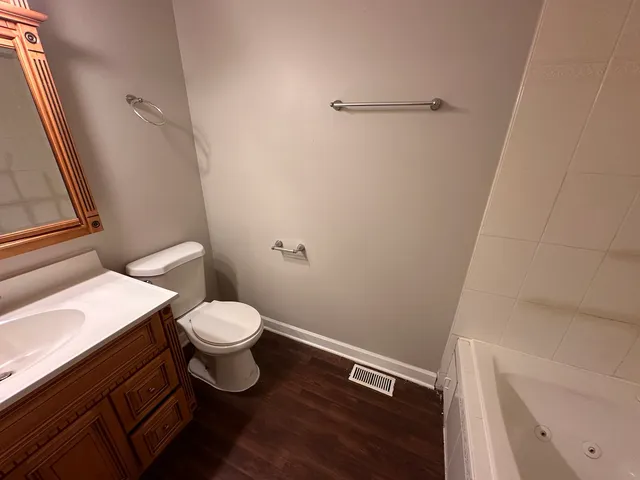 a bathroom with a toilet a sink and wooden floor