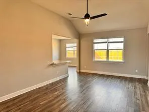 an empty room with wooden floor fan and windows