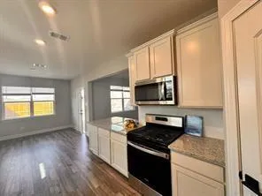 a kitchen with stainless steel appliances granite countertop a stove a sink and a microwave