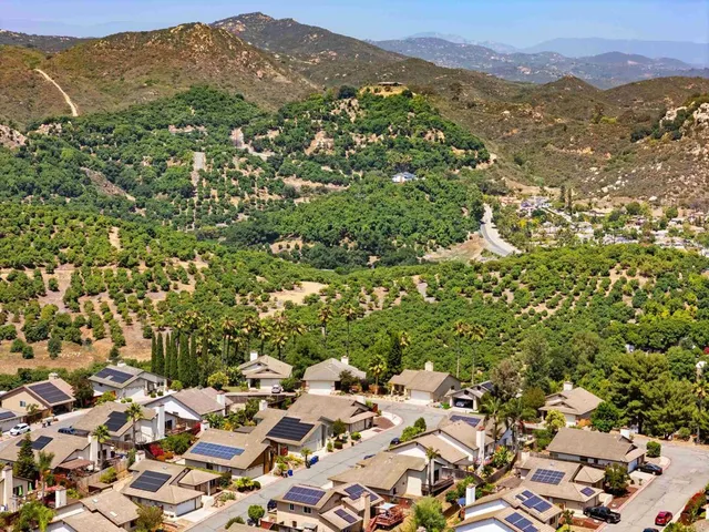 an aerial view of residential house with yard and mountain view in back