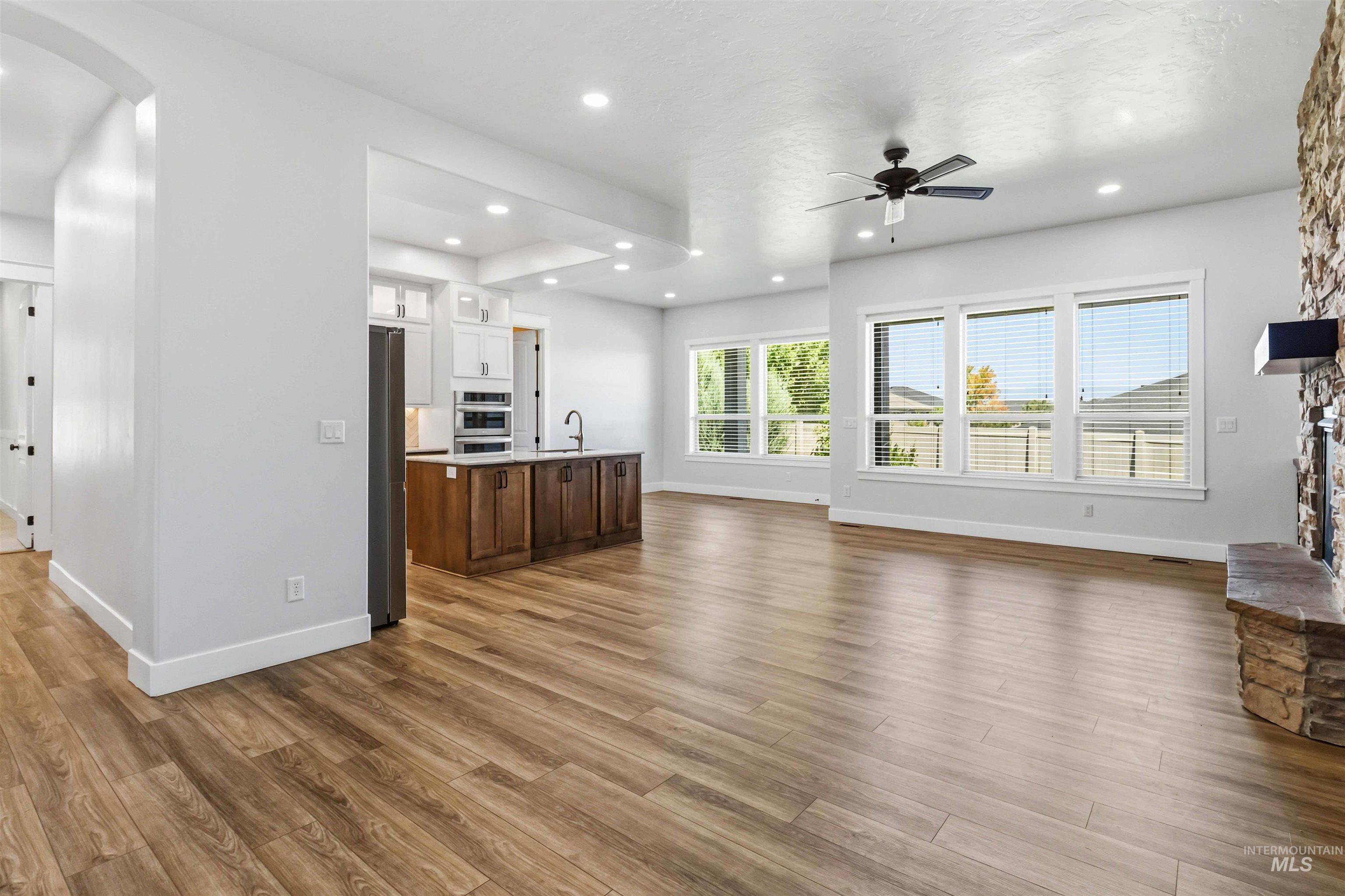 3218 North Cherry Laurel Way Star, ID 83669 - Photo 8 of 50 Spacious living area featuring wood-finish flooring, a stone fireplace with a substantial hearth and wood mantel, and built-in cabinetry with floating shelves