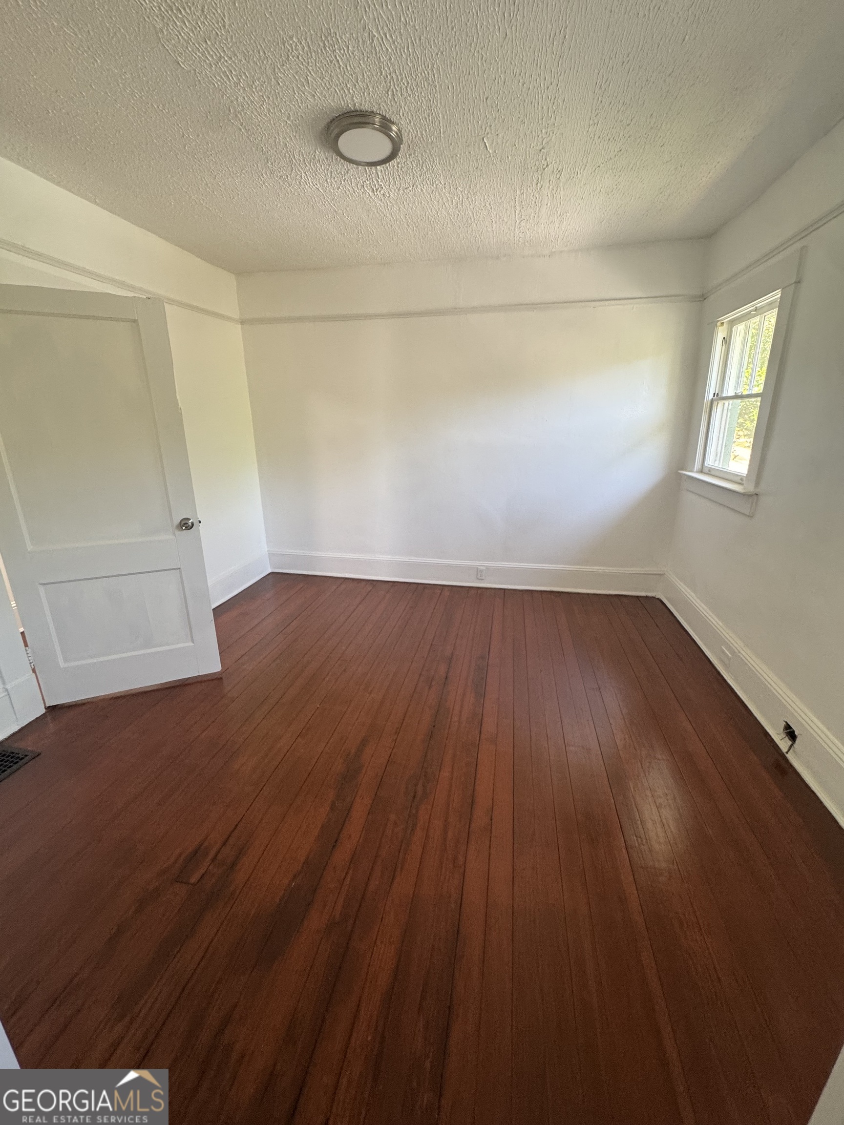 415 Hopkins Street Southwest Atlanta, GA 30310 - Photo 6 of 12 an empty room with wooden floor and windows