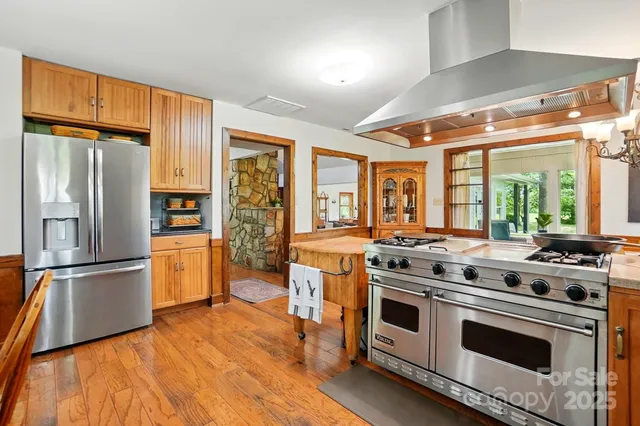 a kitchen with stainless steel appliances a stove a sink dishwasher and wooden cabinets with wooden floor