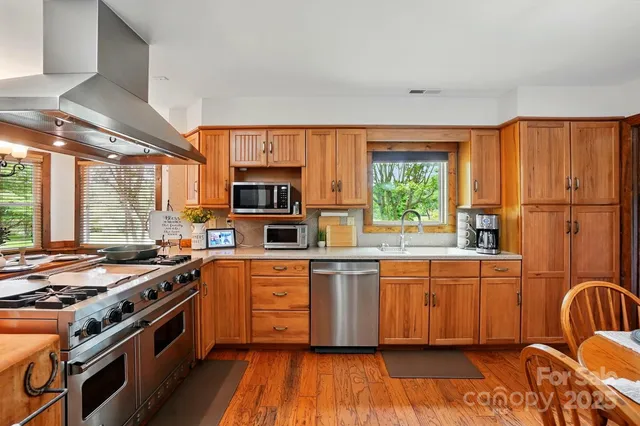 a kitchen with stainless steel appliances kitchen island granite countertop a stove a sink a dining table and chairs with wooden floor