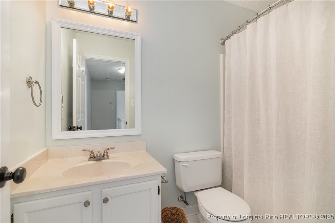 7810 Shuttle Road Fayetteville, NC 28311 - Photo 16 of 25 a bathroom with a sink a toilet and shower curtain
