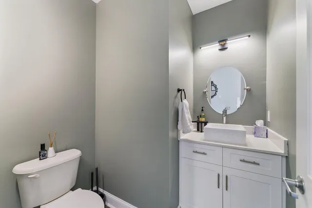 a bathroom with a toilet sink mirror and vanity