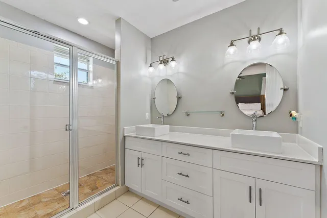a bathroom with a double vanity sink mirror and shower