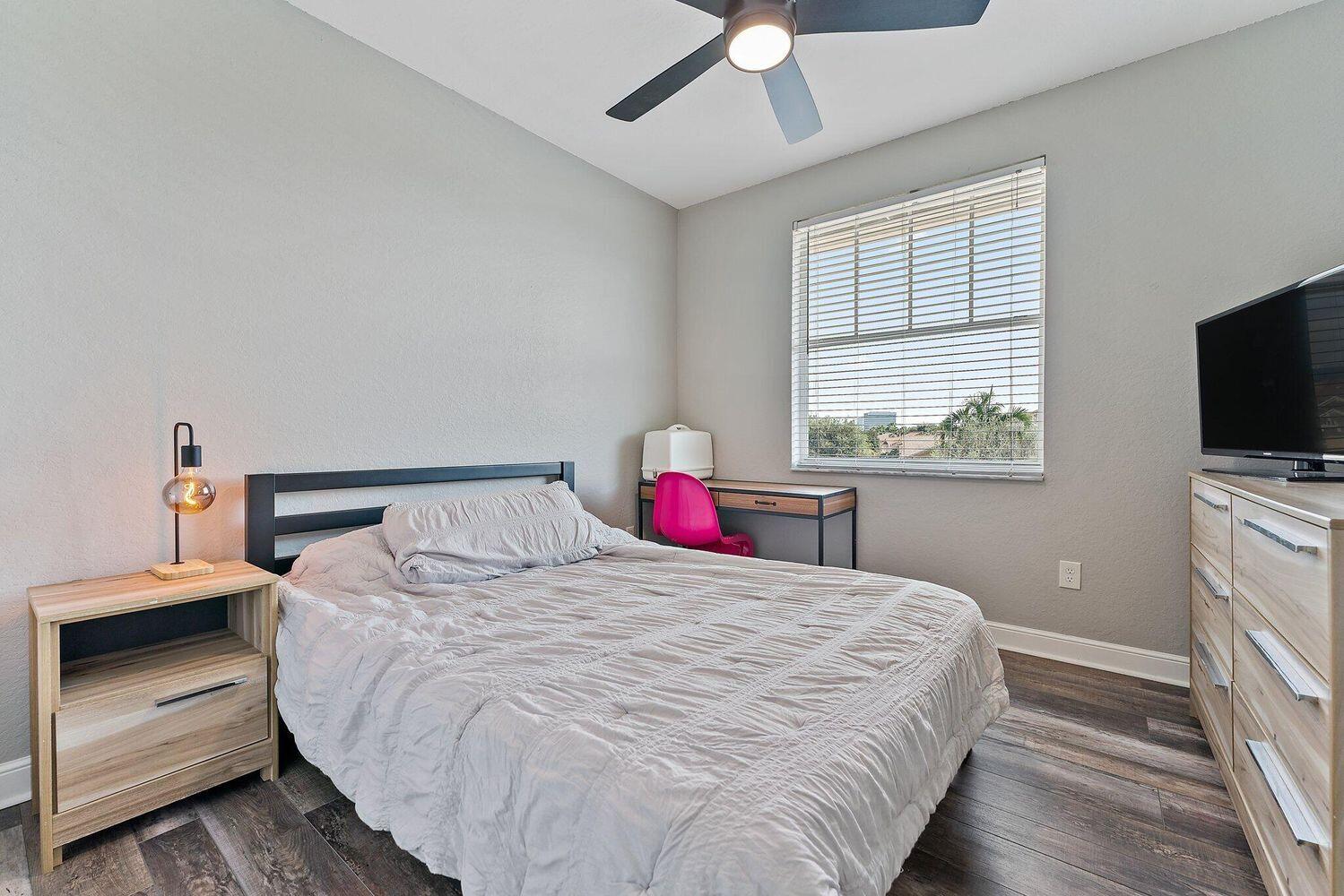 500 Pacific Grove Drive, Unit 8 West Palm Beach, FL 33401 - Photo 19 of 35 a bedroom with a large bed and a flat tv screen on dresser