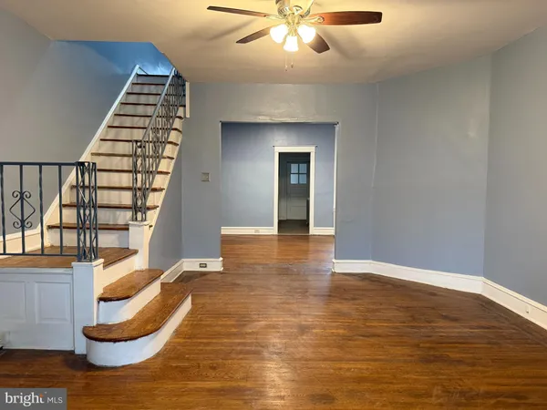 a view of an empty room with wooden floor and stairs