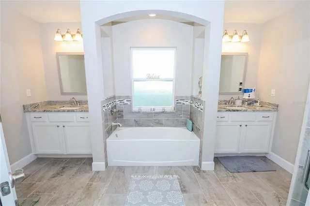 a spacious bathroom with a tub sink and mirror
