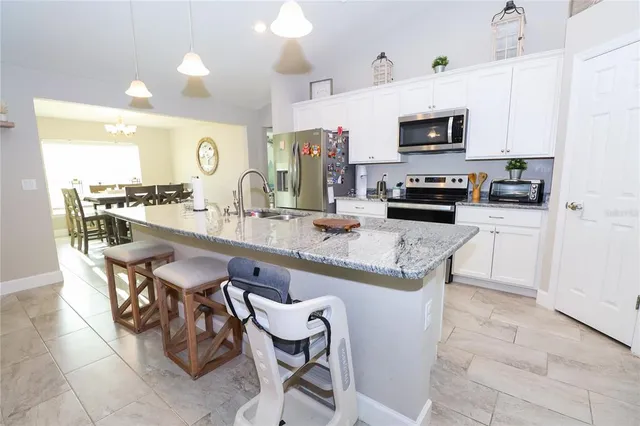 a kitchen with kitchen island granite countertop a sink counter top space appliances and cabinets