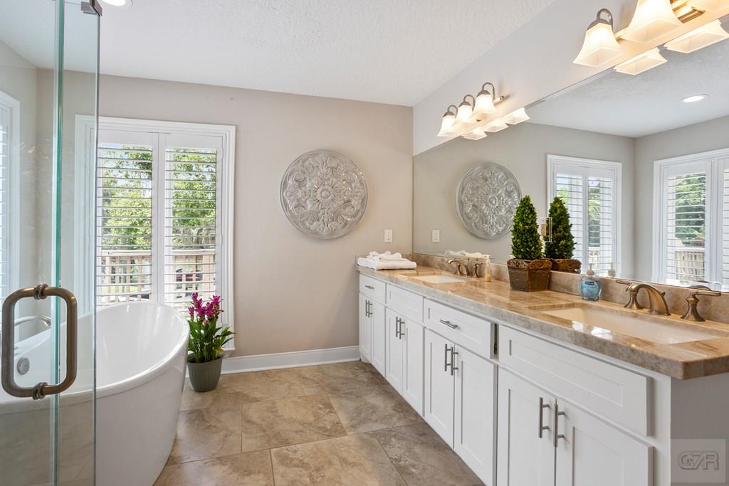 14009 West Hughes Road Dickinson, TX 77539 - Photo 18 of 54 a spacious bathroom with a granite countertop sink a large mirror and a window