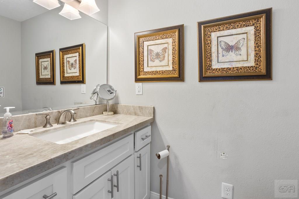 14009 West Hughes Road Dickinson, TX 77539 - Photo 21 of 54 a bathroom with a granite countertop sink mirror and painting on the wall