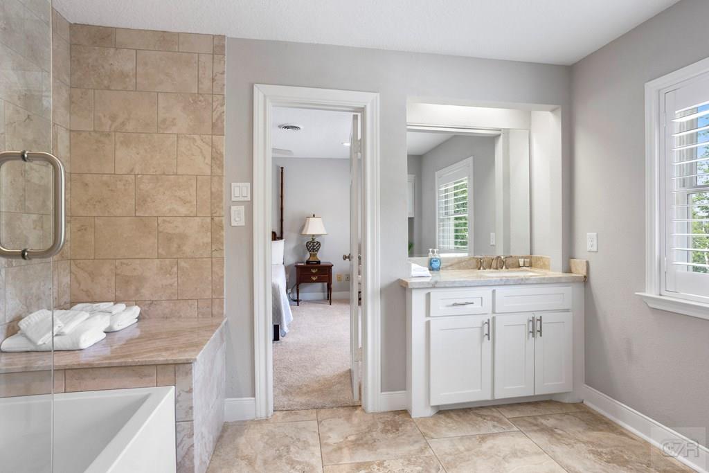 14009 West Hughes Road Dickinson, TX 77539 - Photo 28 of 54 a spacious bathroom with a double vanity sink a mirror and a bathtub