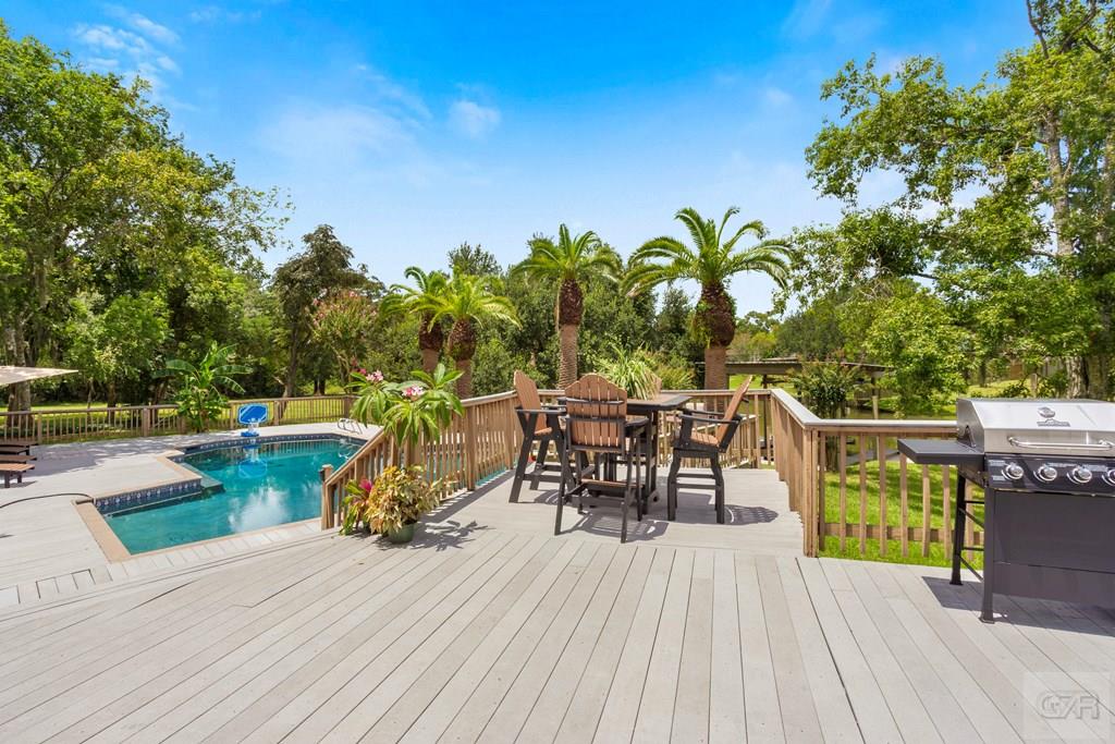 14009 West Hughes Road Dickinson, TX 77539 - Photo 35 of 54 a view of a roof deck with table and chairs couches under an umbrella with wooden floor and fence