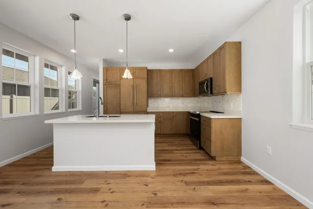 a large kitchen with stainless steel appliances kitchen island a large counter top and a wooden floors