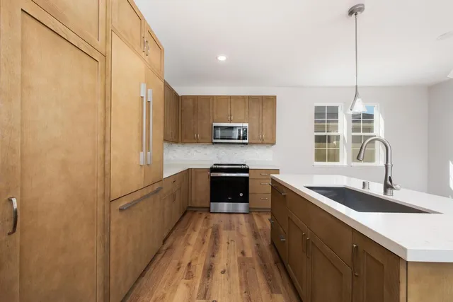 a kitchen with granite countertop a refrigerator a sink dishwasher stove and oven with wooden floor