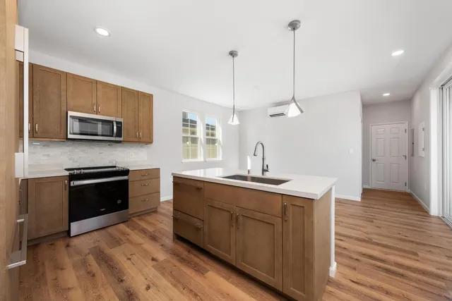 a kitchen with stainless steel appliances kitchen island granite countertop a stove a sink and a wooden floor