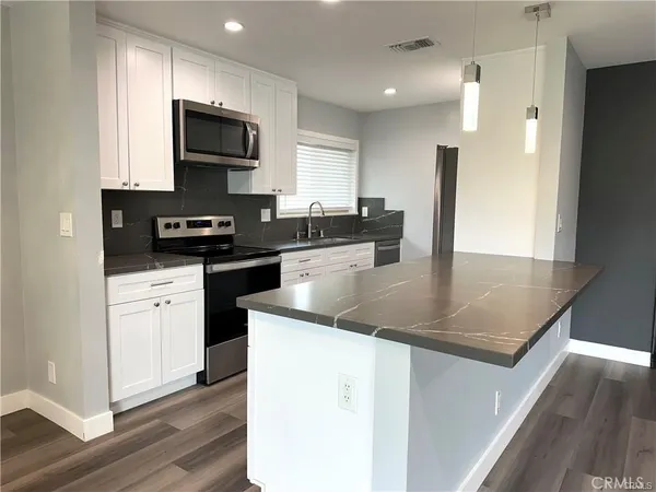 a kitchen with stainless steel appliances granite countertop a sink a stove top oven a counter space and cabinets