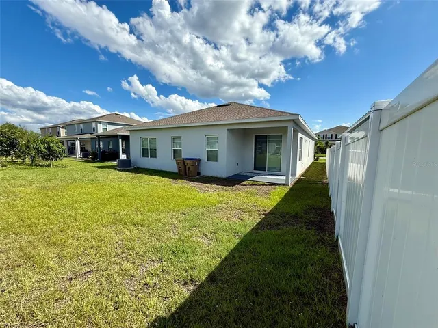 a view of house with a big yard potted plants and large tree