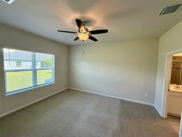 an empty room with windows and fan view