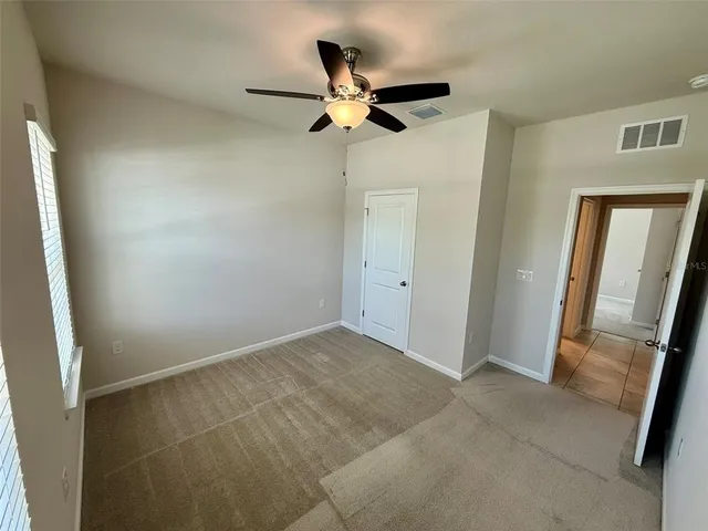 an empty room with wooden door and a ceiling fan