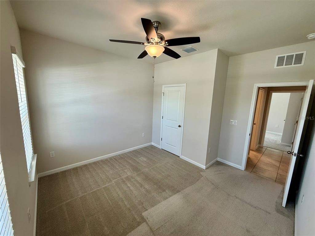 5576 Vigo Loop St. Cloud, FL 34771 - Photo 8 of 17 an empty room with wooden door and a ceiling fan