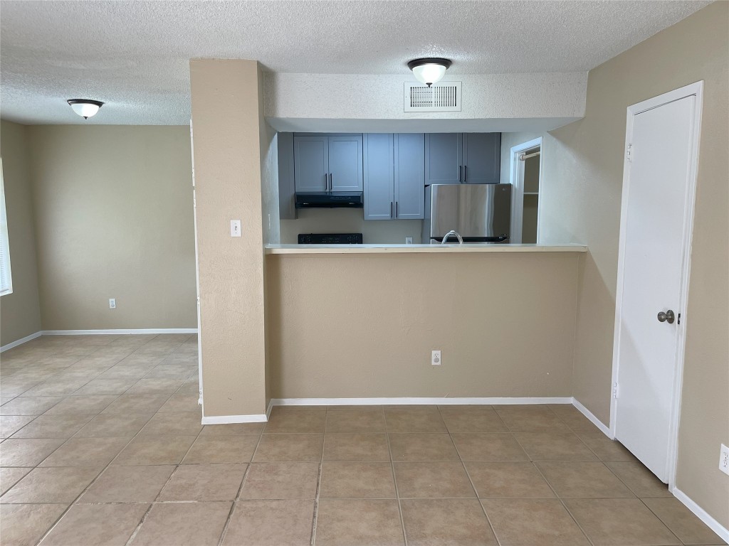 a living room with stainless steel appliances a refrigerator and a cabinets
