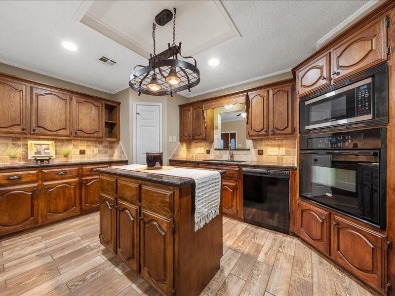 1072 Chapman Road Crawford, TX 76638 - Photo 9 of 39 a kitchen with stainless steel appliances granite countertop a stove top oven a sink dishwasher a dining table and chairs with wooden floor