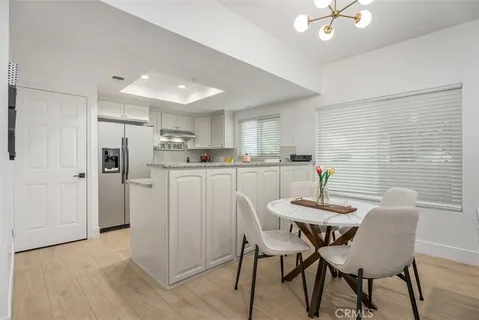 a kitchen with stainless steel appliances kitchen island granite countertop a dining table chairs and a refrigerator