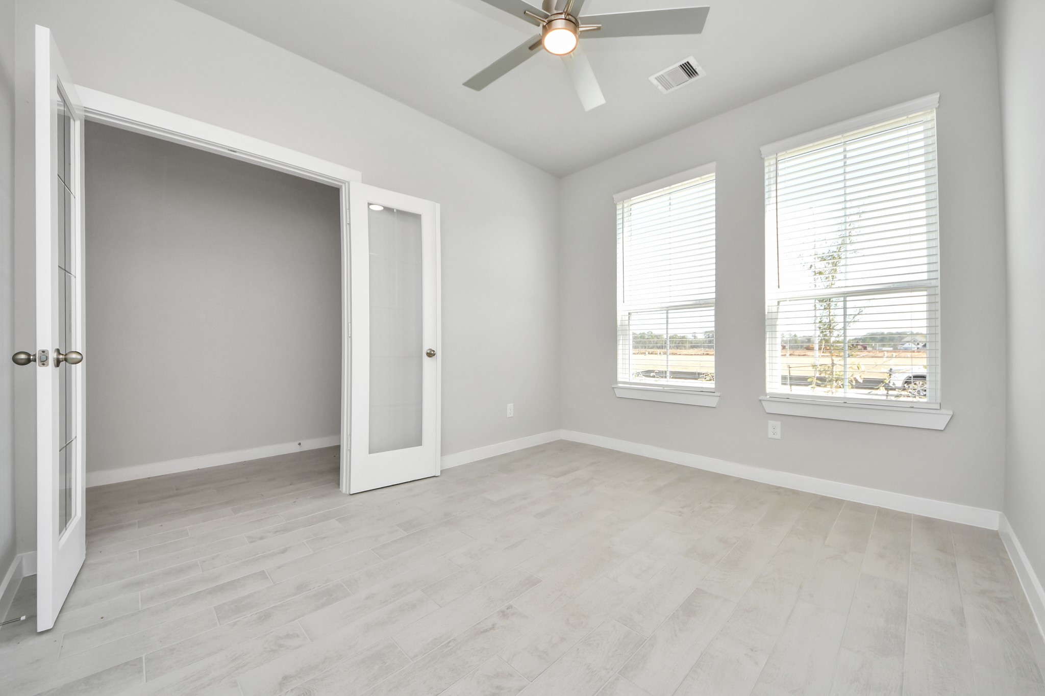2934 Burris Park Drive Spring, TX 77373 - Photo 4 of 35 Experience the perfect blend of sophistication and warmth in this home office, boasting elegant wood-look tile flooring and flooded with natural light from expansive windows and French doors. Sample photo of completed home with similar floor plan. Actual colors and selections may vary.