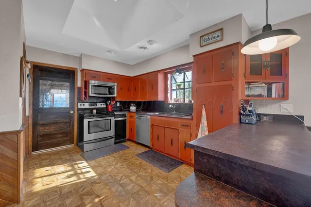 a kitchen with stainless steel appliances kitchen island granite countertop a refrigerator stove top oven and sink