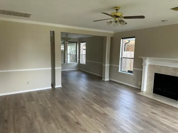 a view of an empty room with window and wooden floor