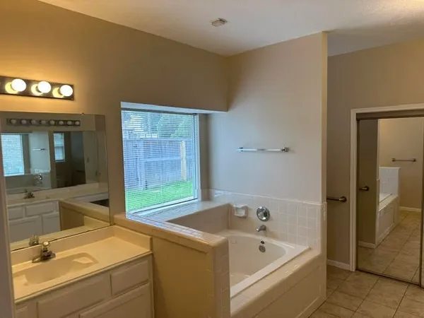 a bathroom with a tub sink and mirror